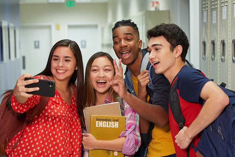 teens taking selfie in school hallway